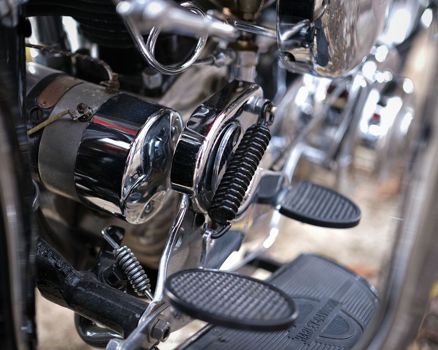 Detail shots of motorcycle foot pegs and controls mounted on chrome engine components in dramatic lighting.