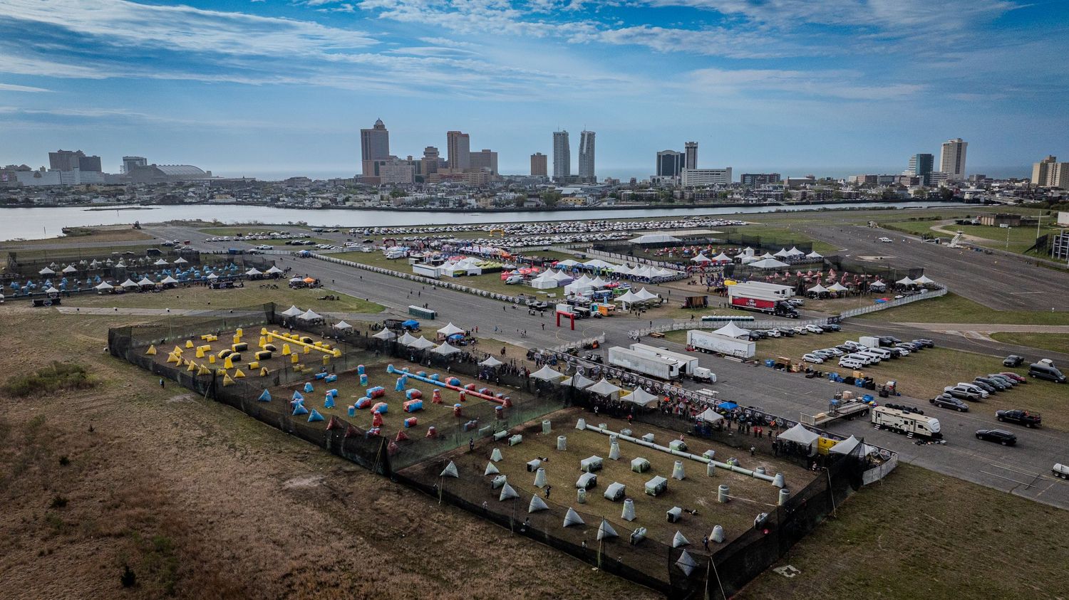 Panoramic aerial view of a large commercial vehicle storage lot with shipping containers and trucks under blue skies.