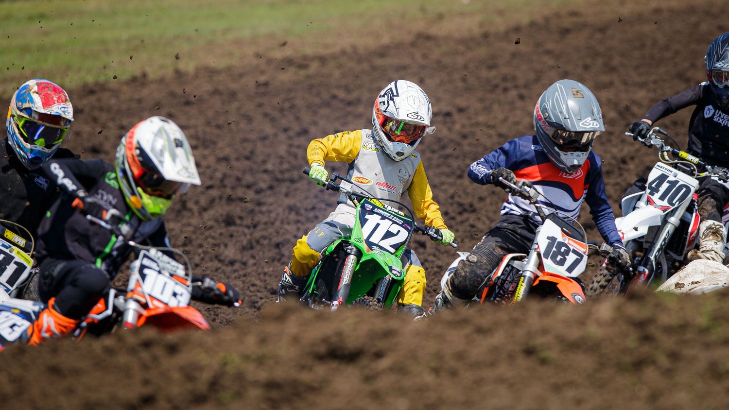 Motocross riders battling for position during an intense race on dirt track.