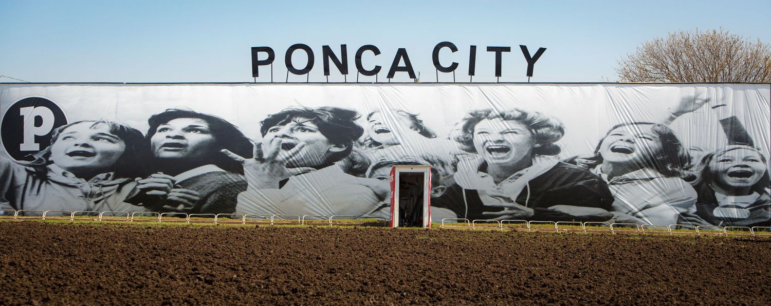 Ponca City sign with large-scale portrait mural displayed on exterior wall.
