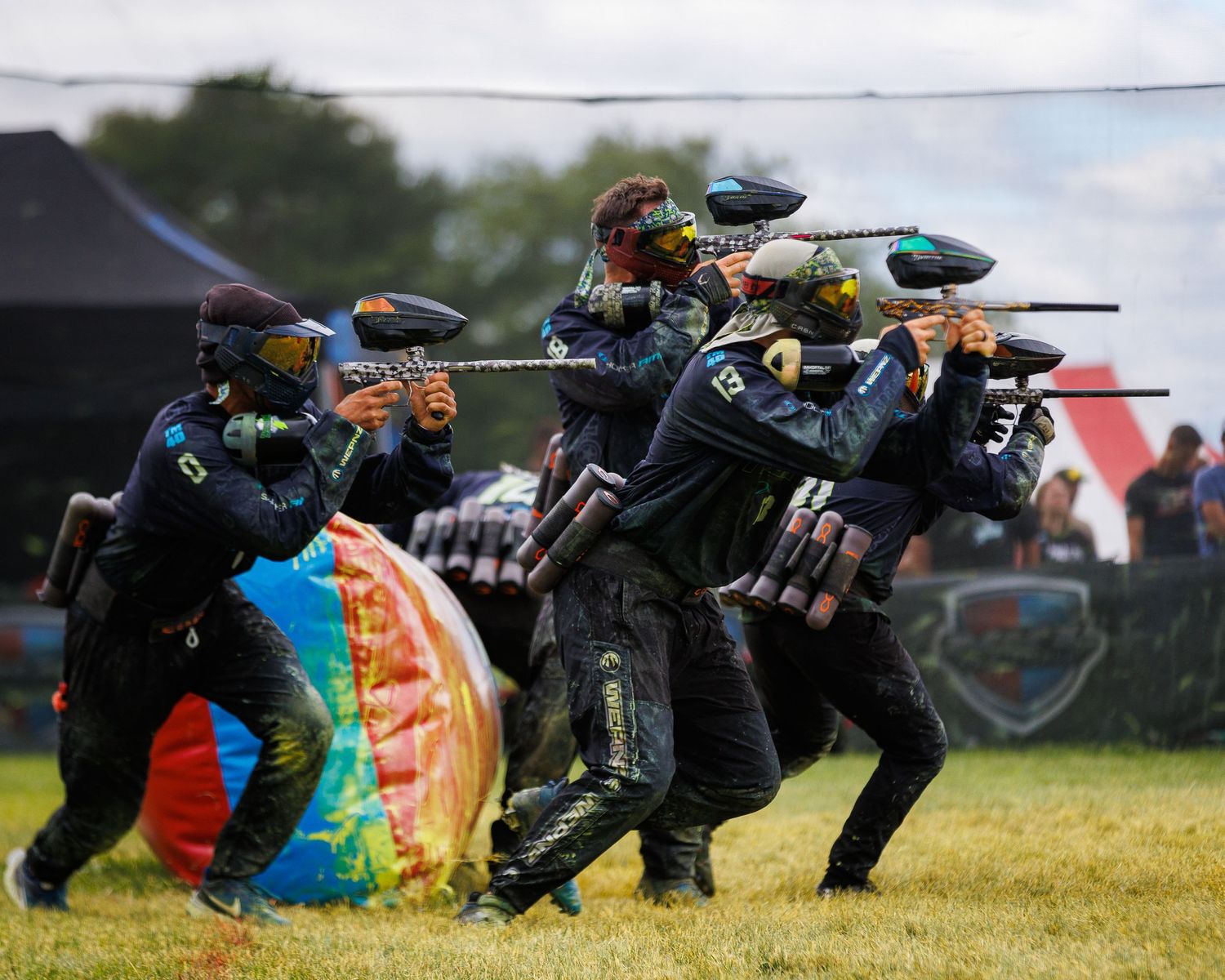 Team of paintball players taking tactical positions behind inflatable bunkers during tournament play.