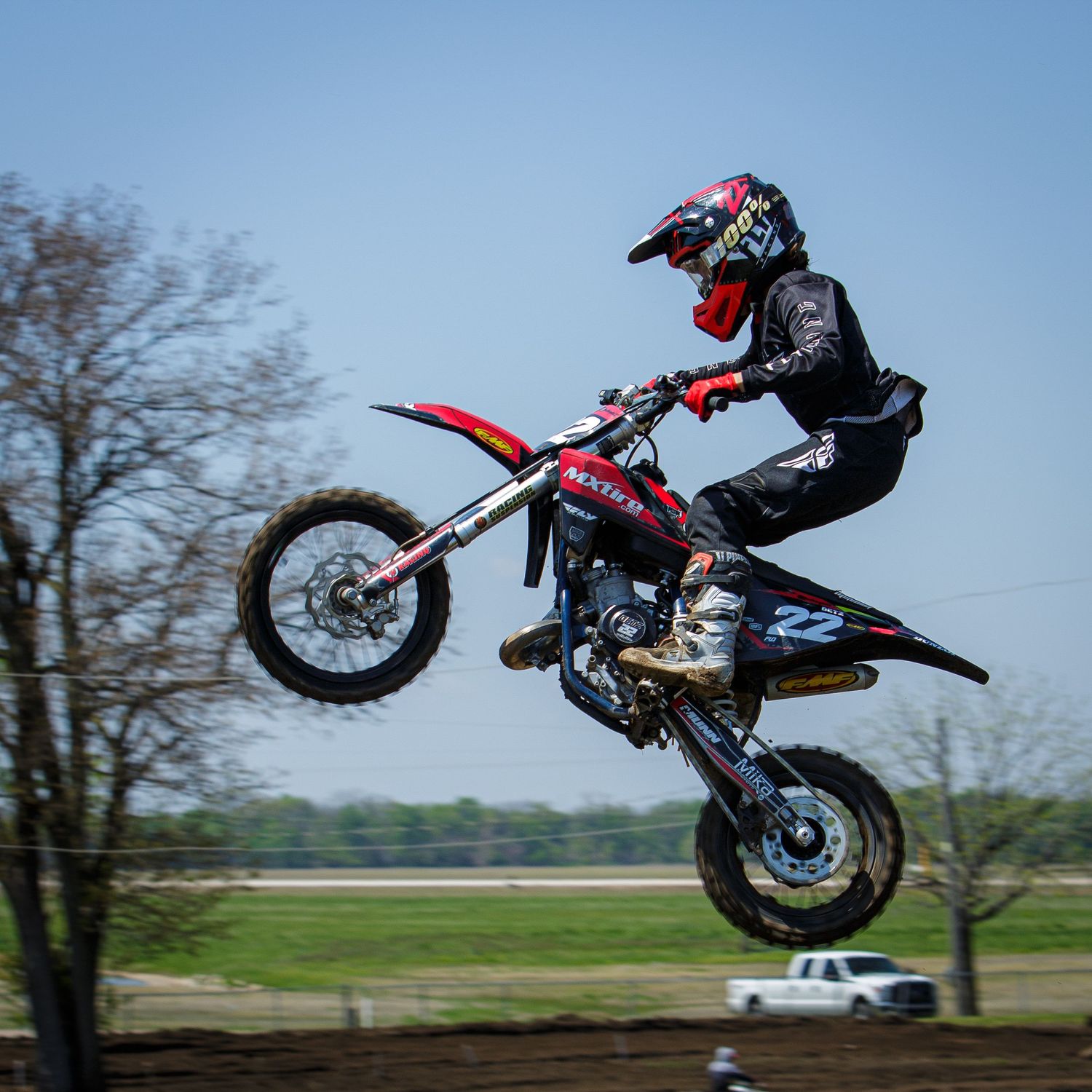 Motocross rider performs aerial stunt with dirt bike against blue sky.