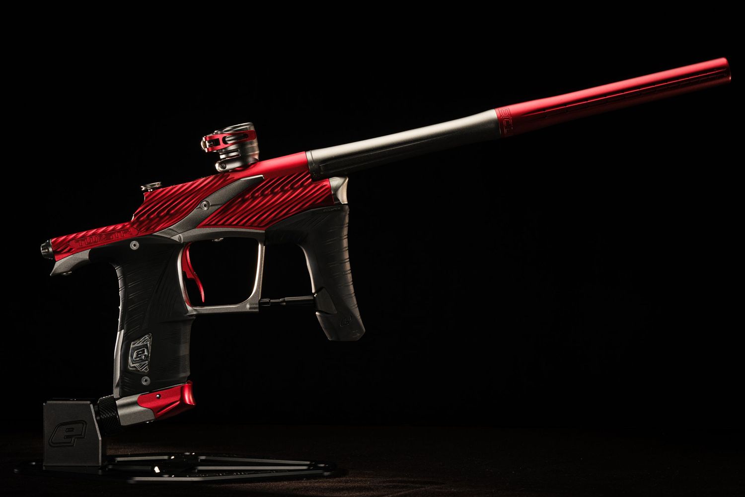 Red paintball marker gun isolated on black background with dramatic lighting.