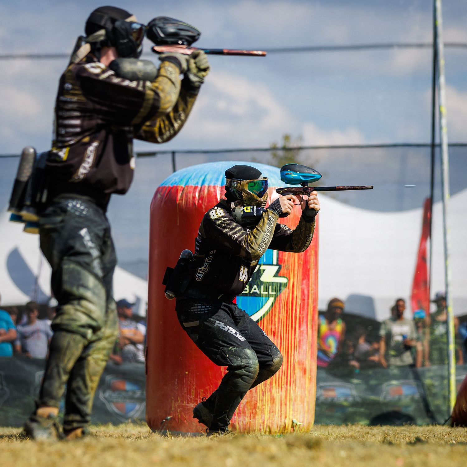 Two paintball players in tactical gear taking aim from behind bunkers.