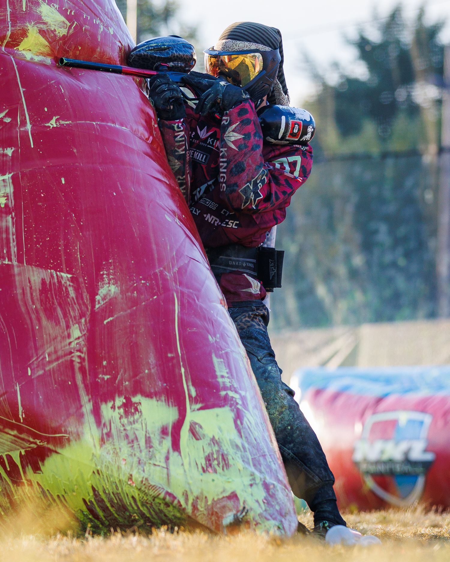 Paintball competitor takes cover behind pink inflatable bunker during intense match.