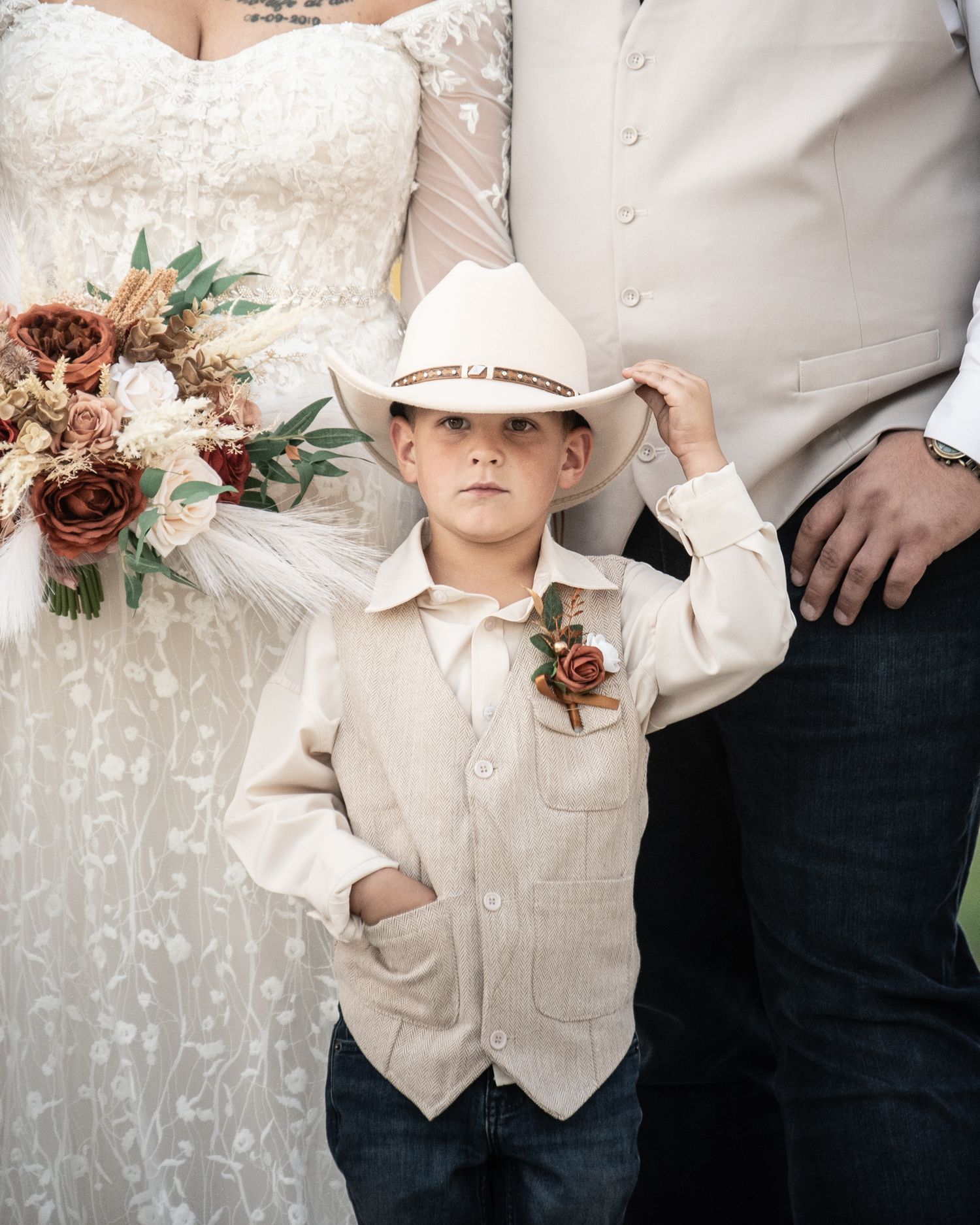 Wedding party members in cream and white attire stand against a textured backdrop.