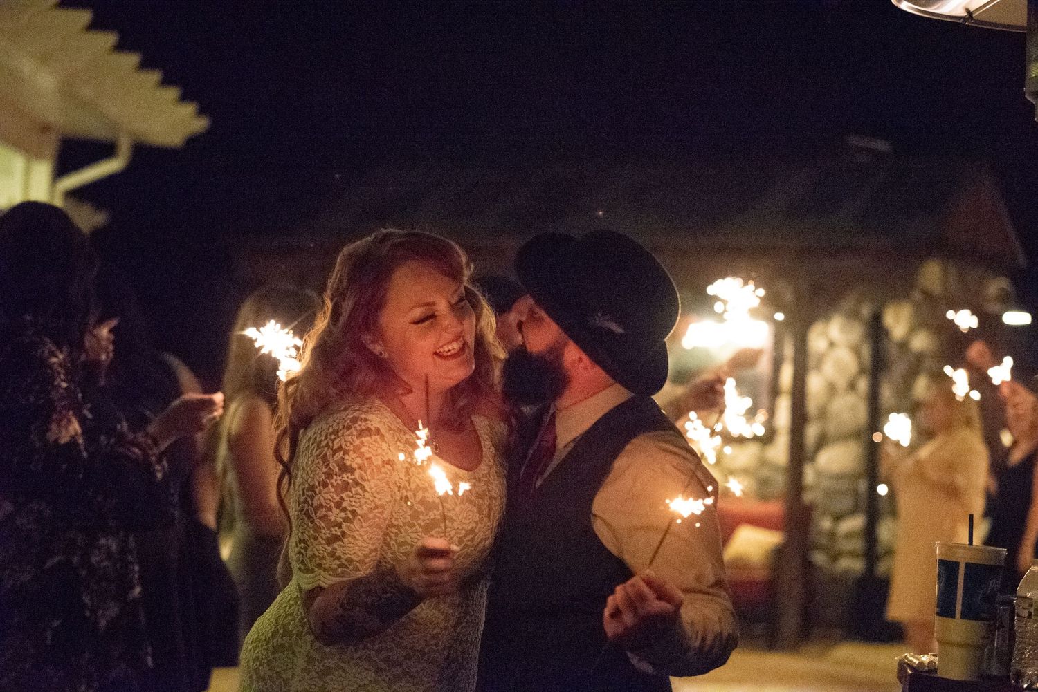Couple shares an intimate dance moment at a candlelit evening celebration with glowing lights in background.