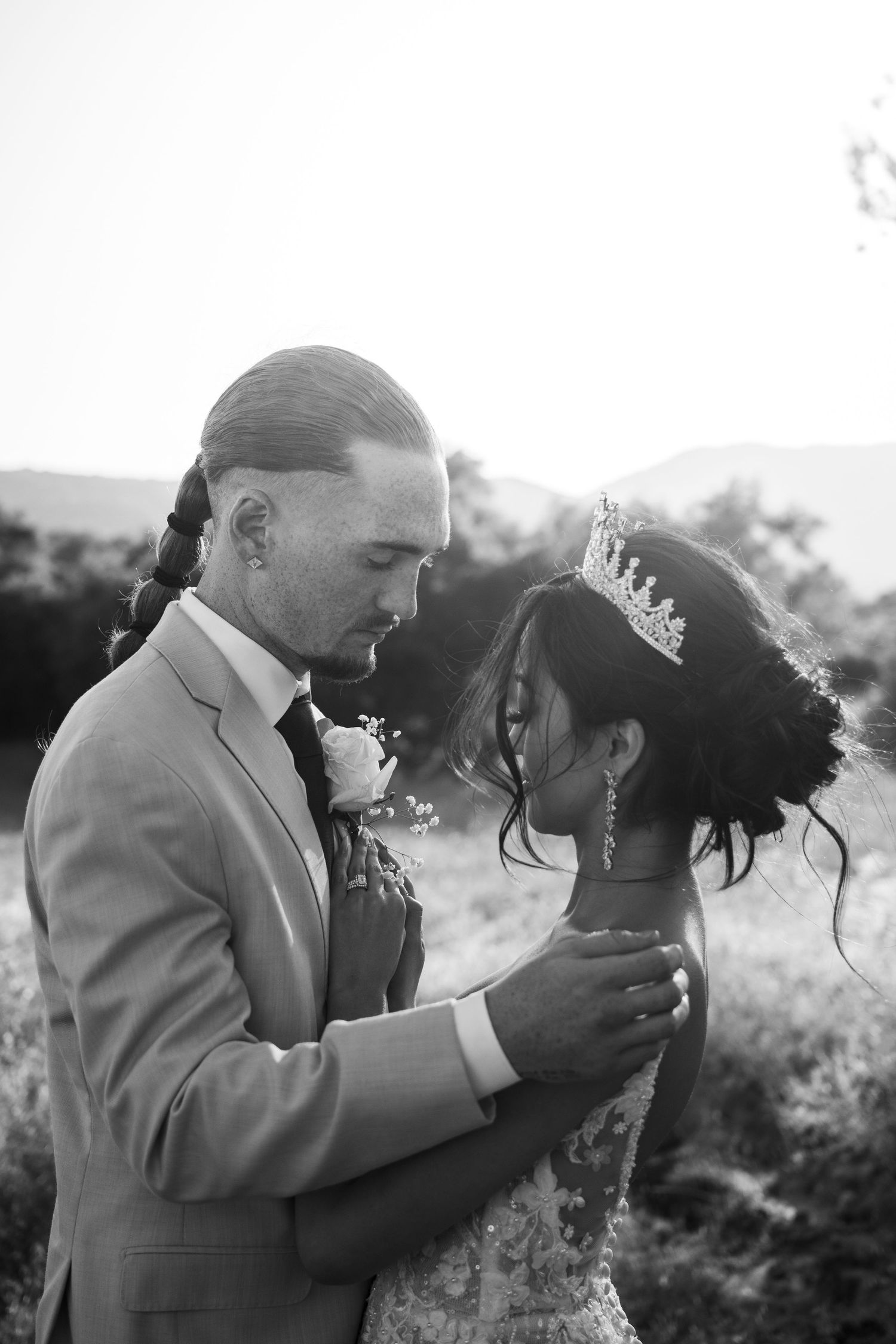 Intimate black and white wedding portrait of couple with tiara in outdoor setting.