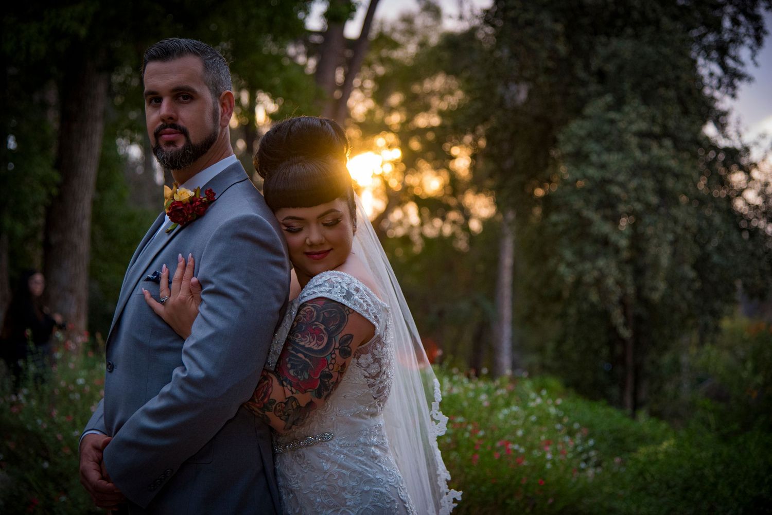 A couple stands back-to-back during sunset in a park, with the bride wearing a white dress and veil.