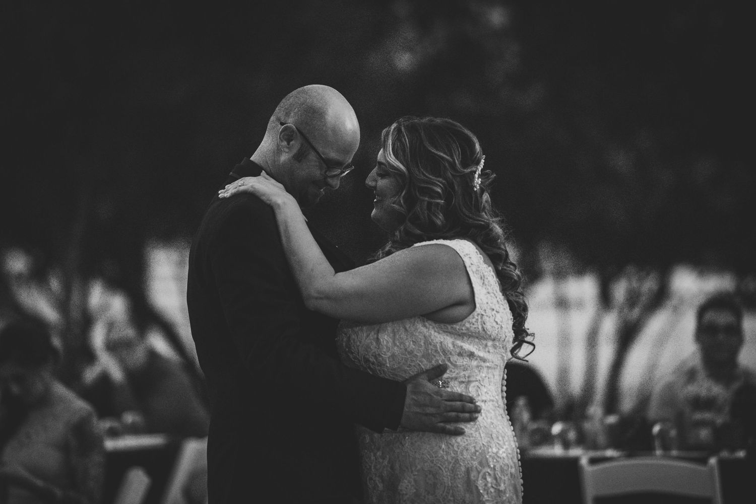 Black and white photo of a bride and groom sharing a romantic dance at their wedding reception.