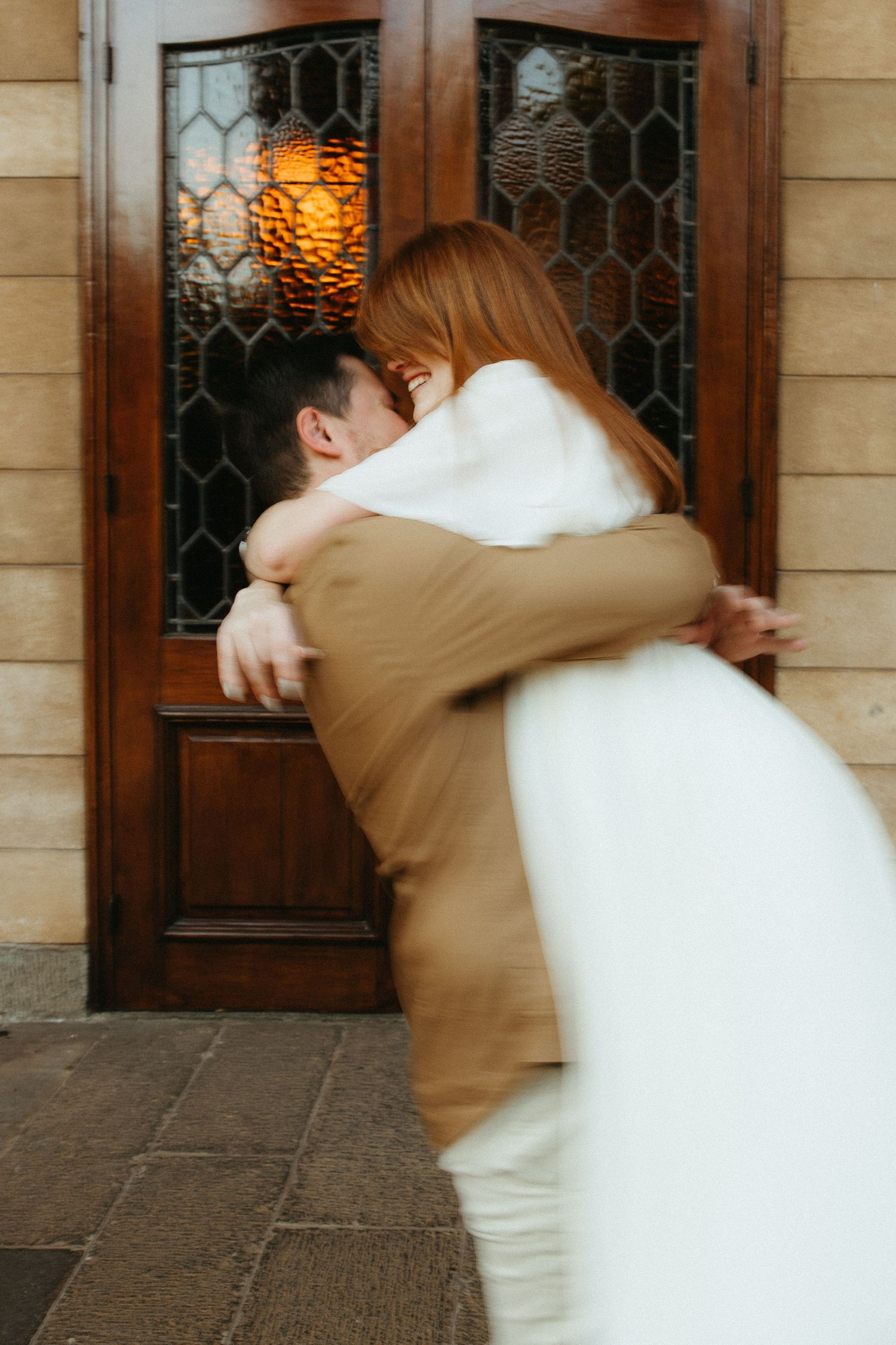 Engaged couple spinning in a circle while he picks her up in a hug position.