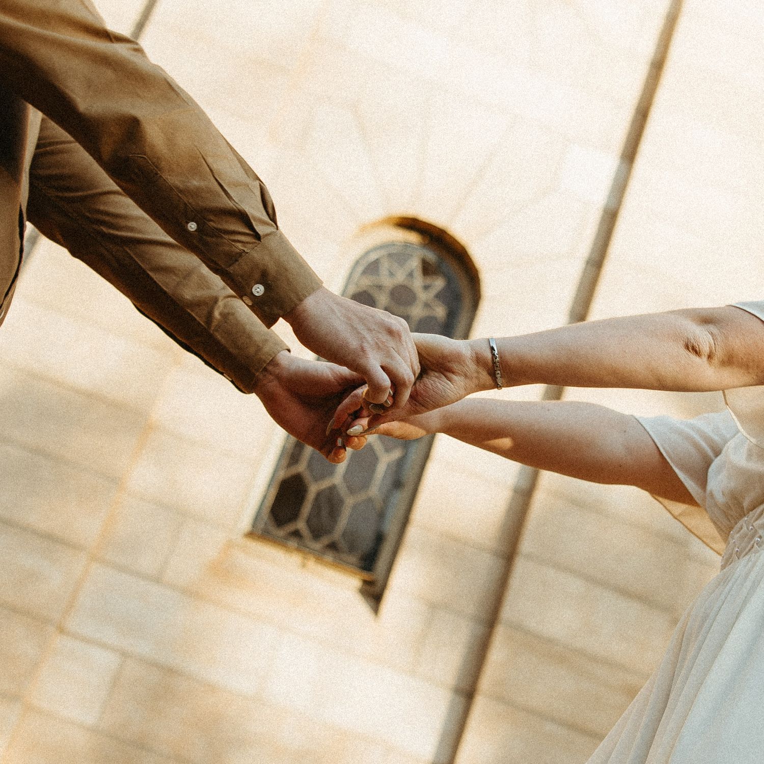 Close up of the couple's hands holding while facing each other.