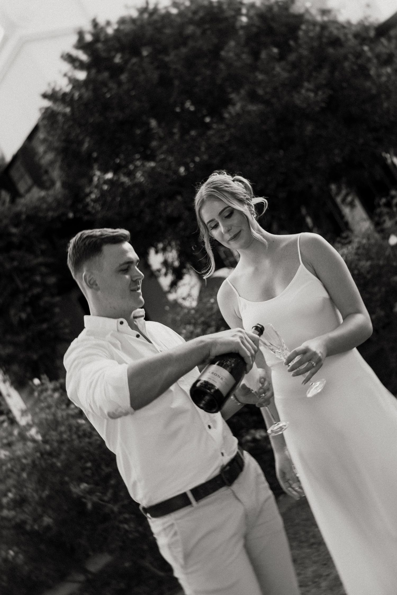 Engaged couple pouring champagne to celebrate their engagement. Black and White.