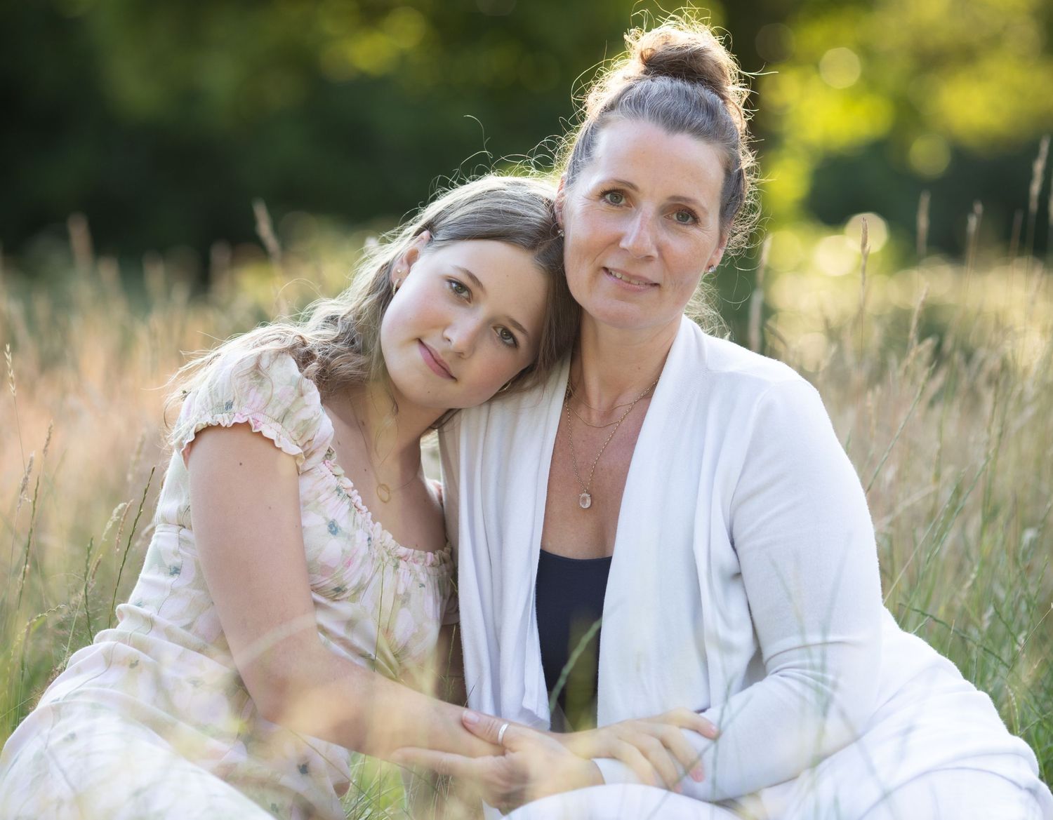 Mother and daughter in white outfits posing in golden summer field.