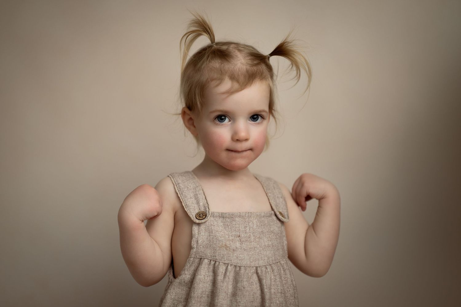 Portrett av jente med blond hestehale som ser rett i kamera – klassisk studiobilde med naturlig uttrykk