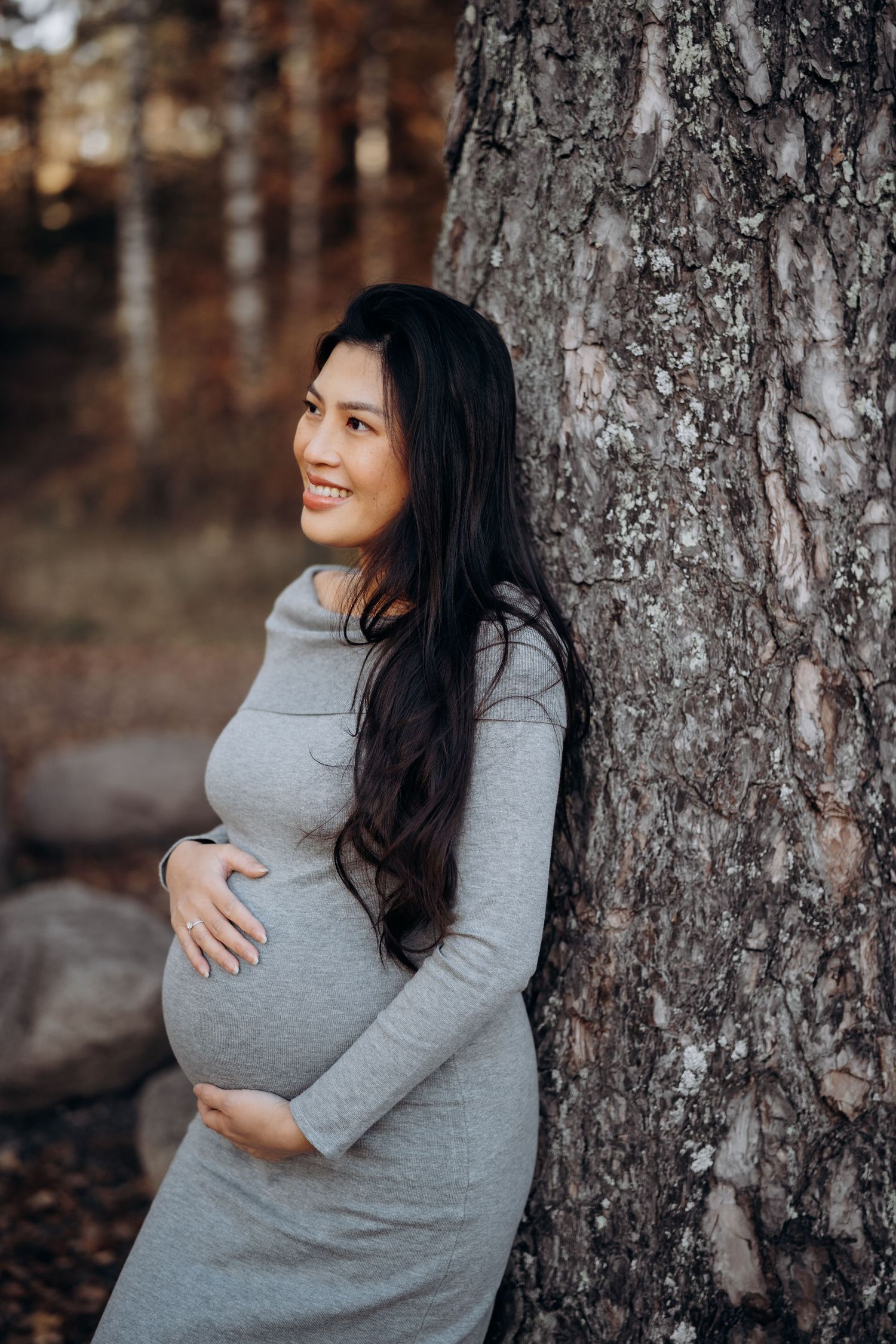 Portrett fotografering av gravid dame - står foran et tre, i en grå kjole.