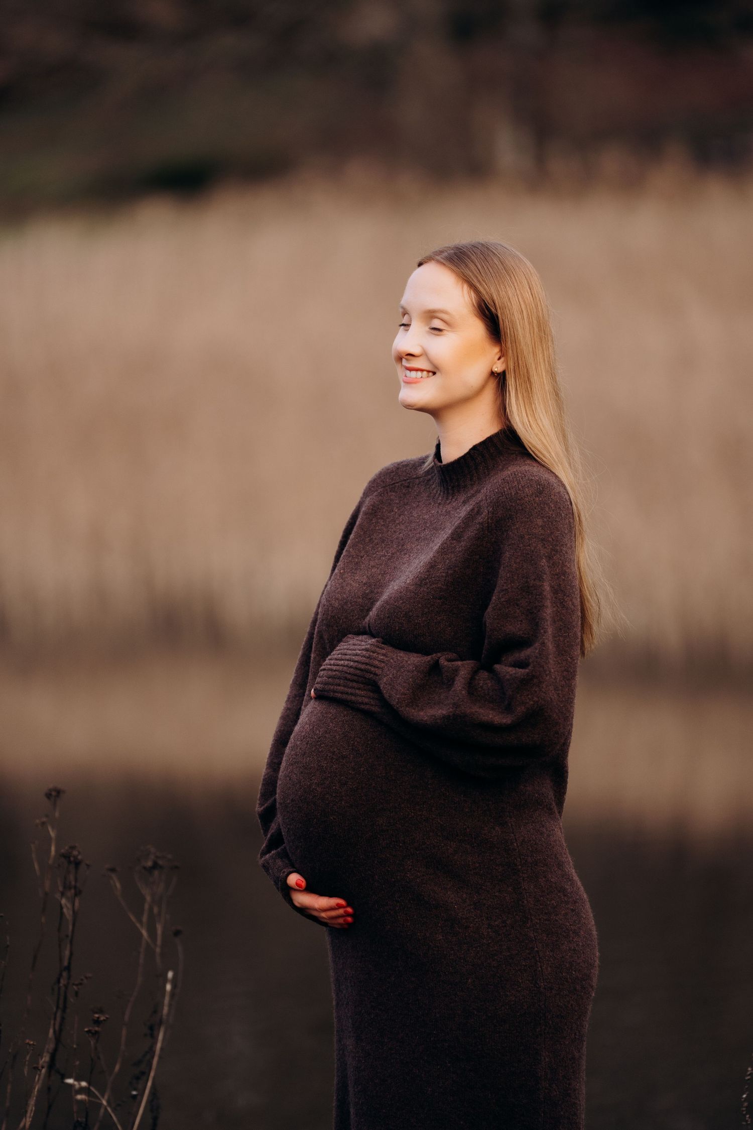 Portrett fotografering av gravid dame - står ute foran en innsjø.