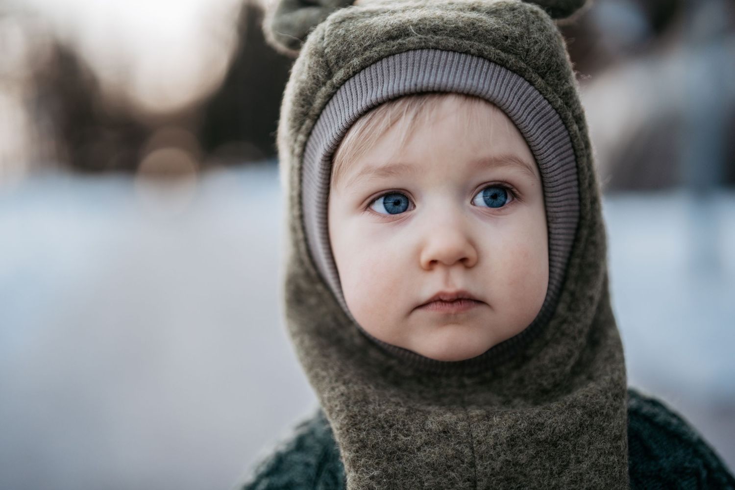 Barnefoto av en ett år gammel gutt. Utendørsfoto om vinteren. Portrettbilde.