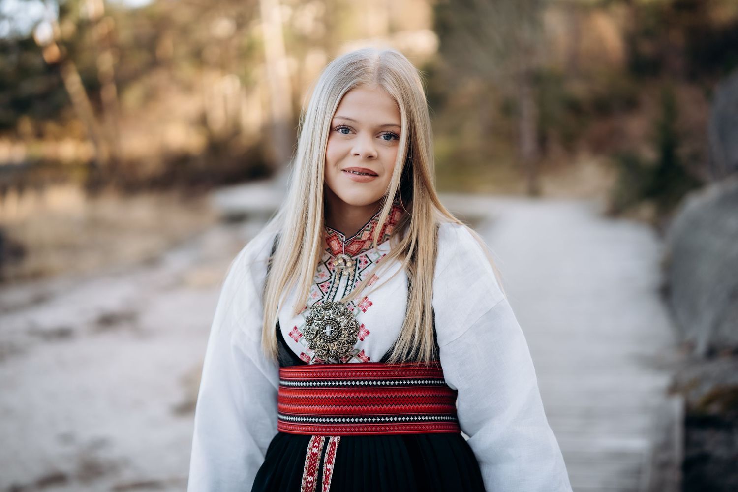 Konfirmasjonsfoto av ei jente i bunad som smiler mot kamera.