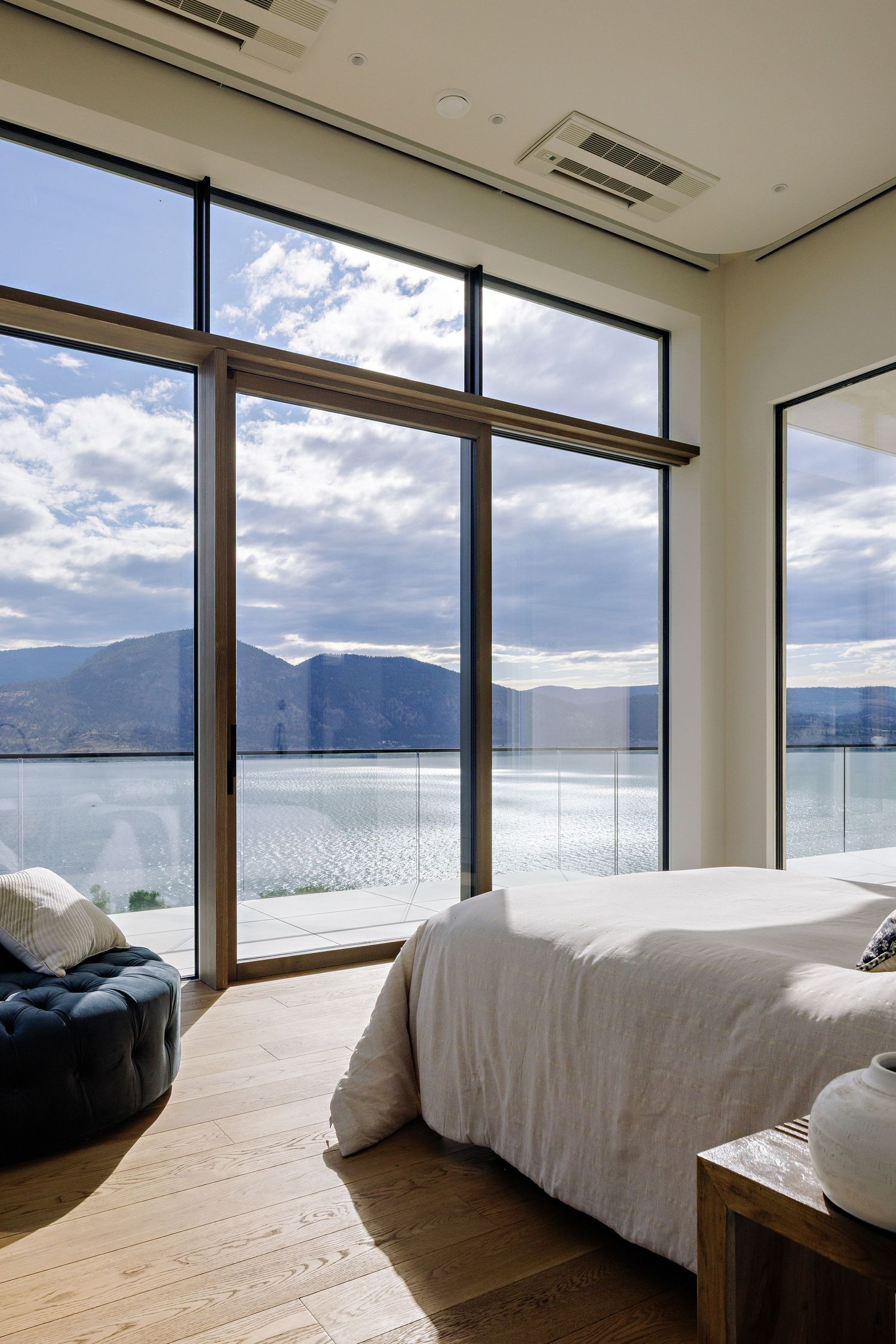 Modern bedroom with panoramic windows showcasing stunning mountain and lake views across five connected photos.
