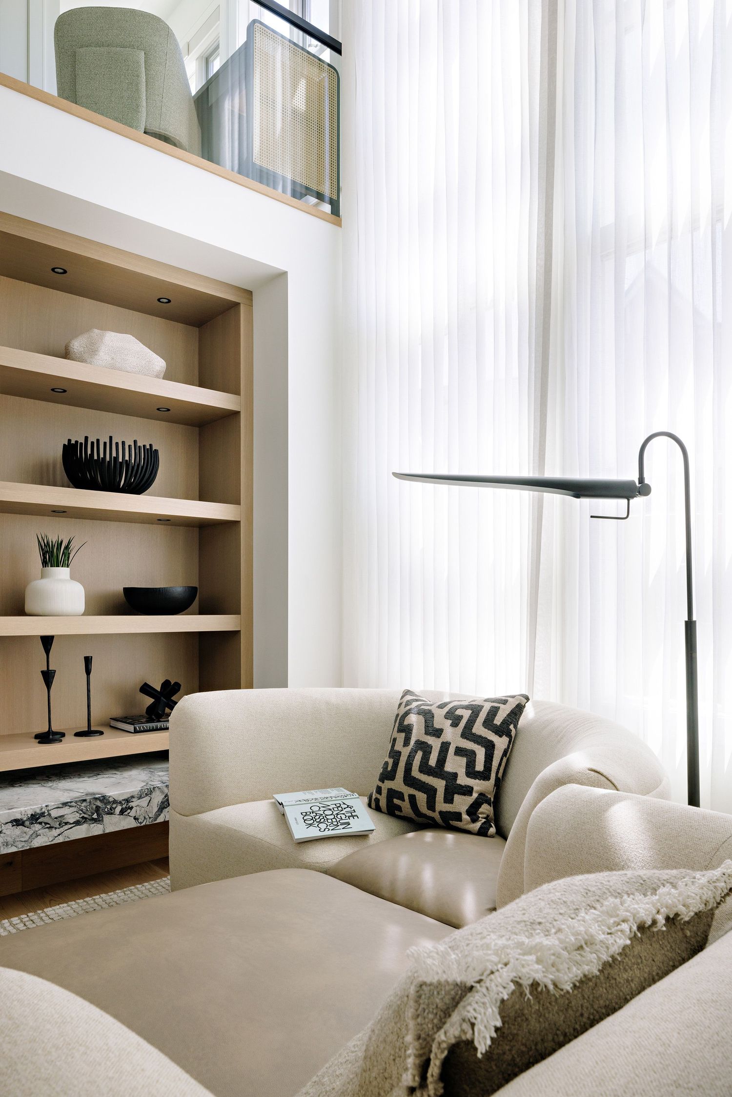 Cozy living area with built-in shelving and comfortable cream sectional with geometric pillows.