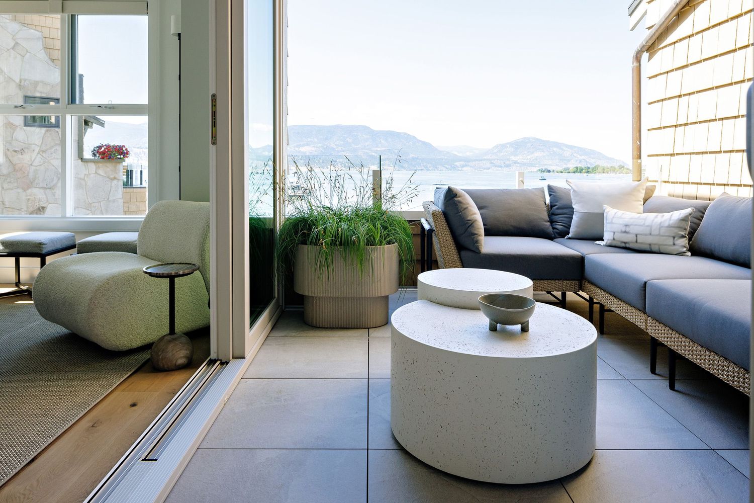 Modern outdoor terrace with grey sectional sofa and round concrete coffee table.