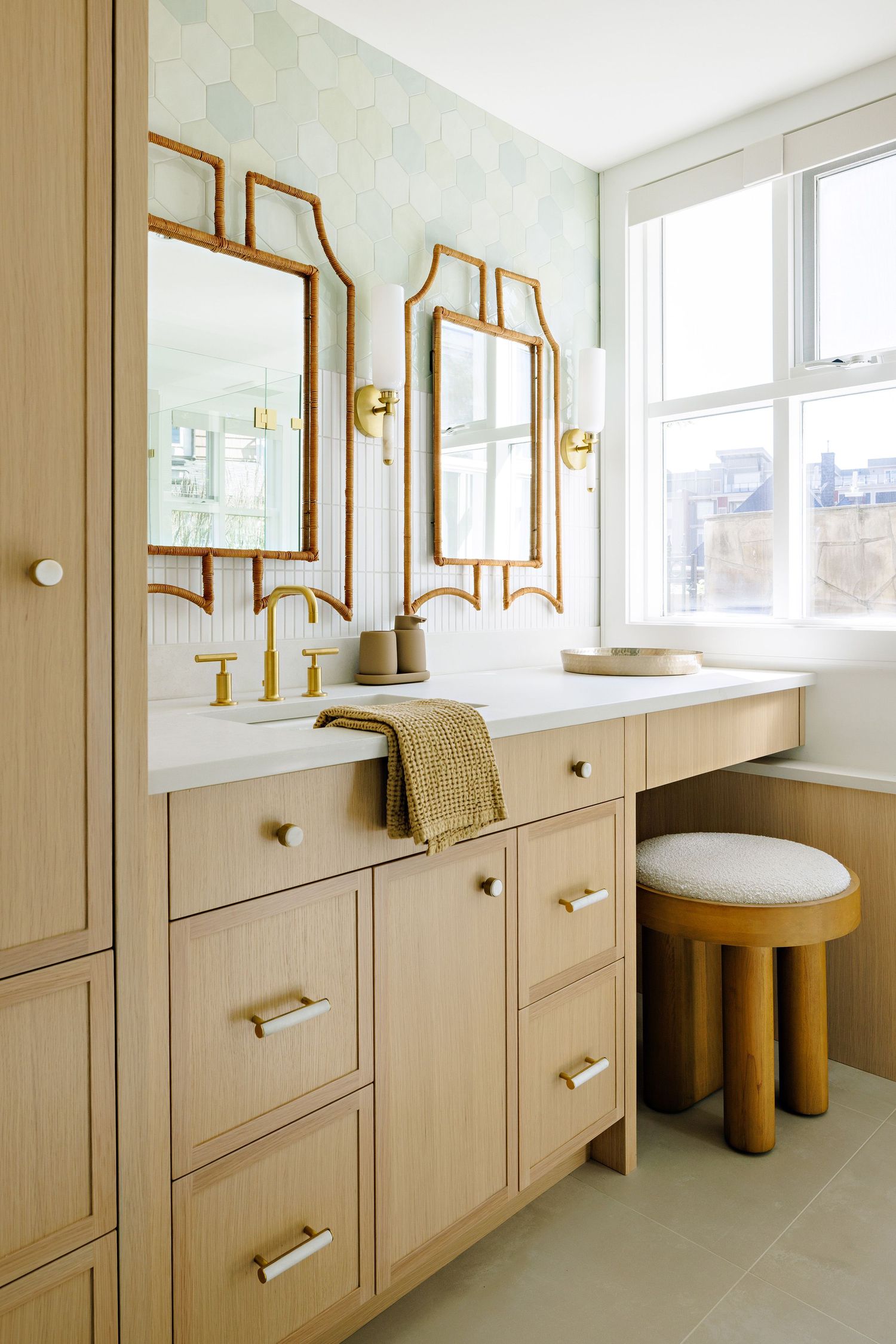 Elegant bathroom vanity with beige cabinetry, gold-framed mirrors, and brass hardware.