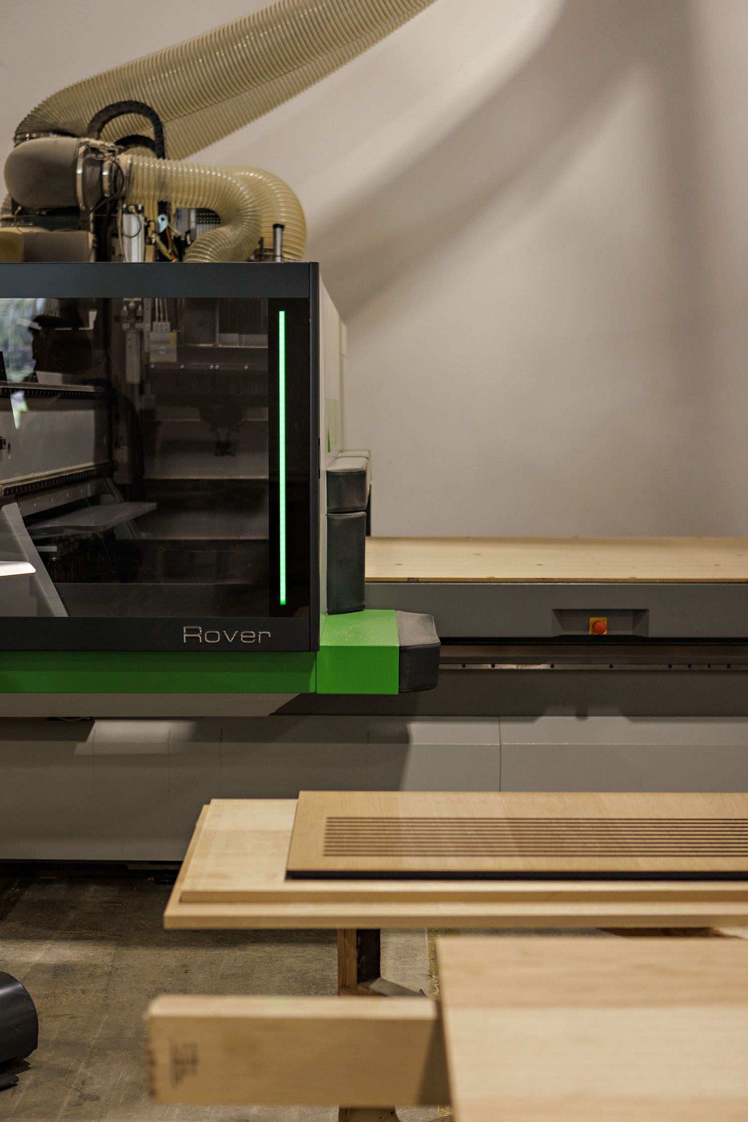 CNC machine tool head moves along track while cutting wooden boards on manufacturing workbench.