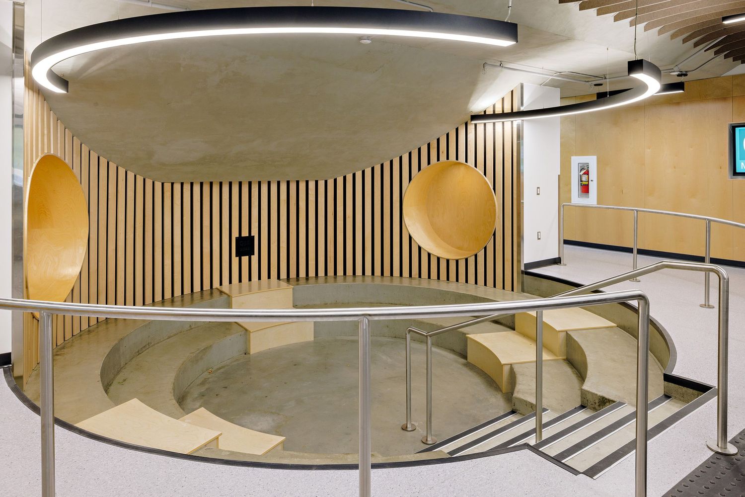 Modern interior hallway with curved design features circular gold accent panels and vertical wooden slat walls.