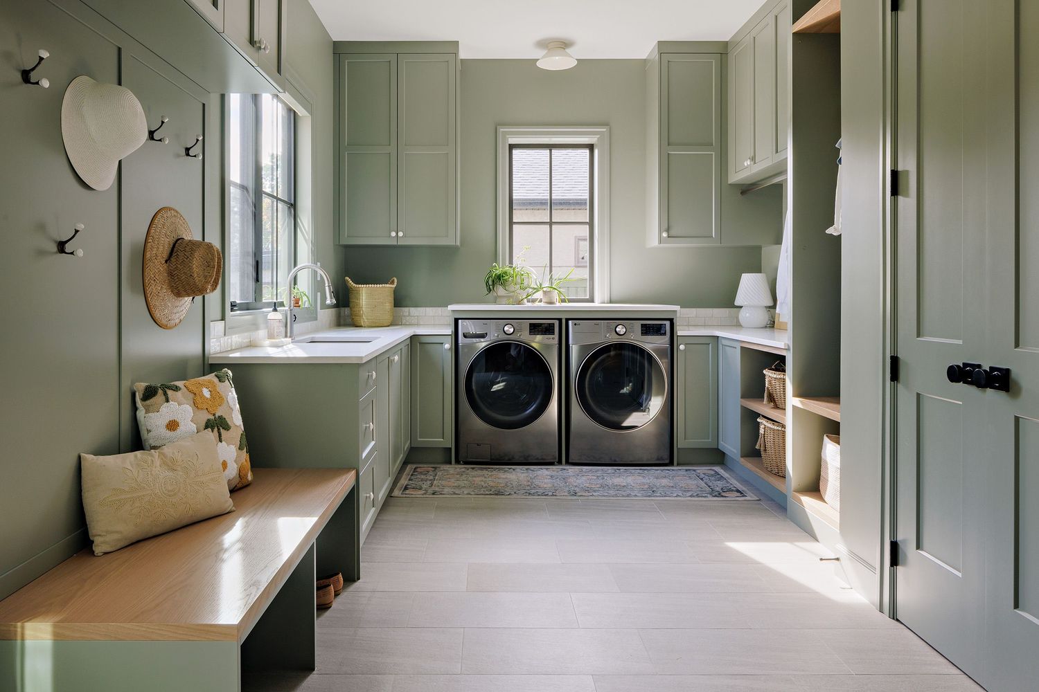 Modern laundry room with sage green cabinets, wooden countertops, and built-in storage showcasing elegant design details.