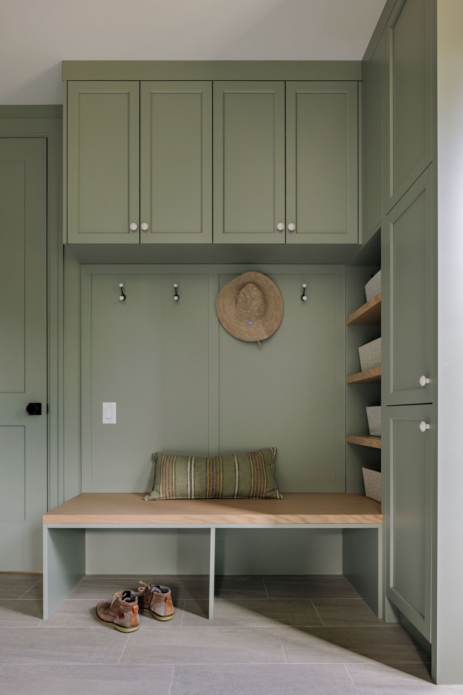 Modern mudroom with sage green built-in cabinets and wooden bench seating along the wall.