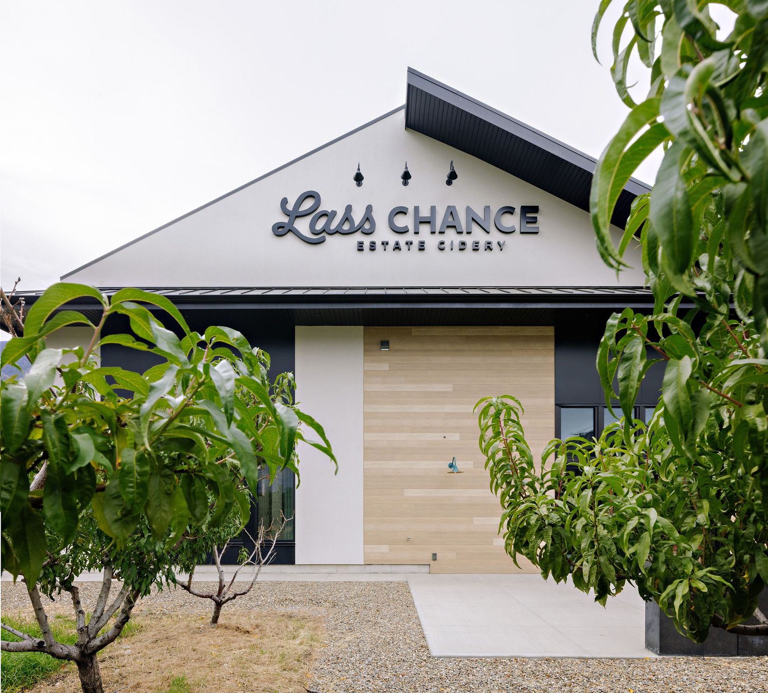 Modern coffee shop facade with wood accents and black trim featuring Last Chance signage on white exterior wall.