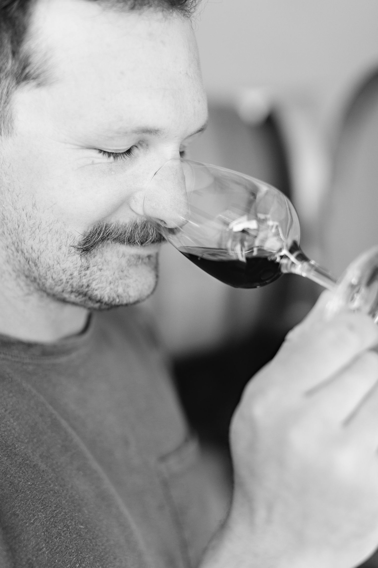 Black and white photograph of someone smelling wine from a glass during a wine tasting.