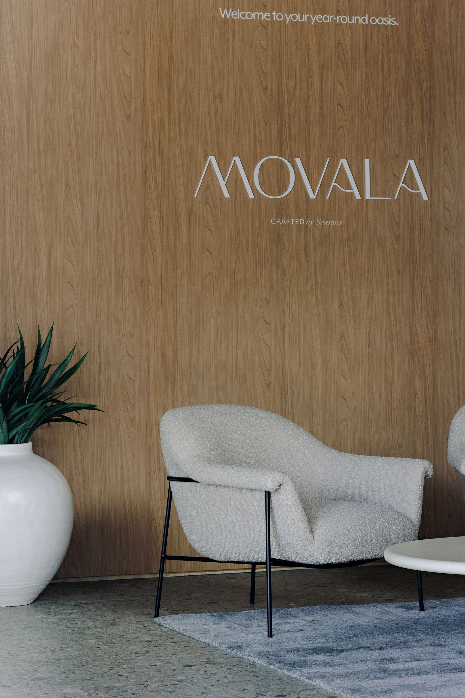 Modern minimalist reception area with Movala branding featuring a white accent chair and wooden wall paneling.
