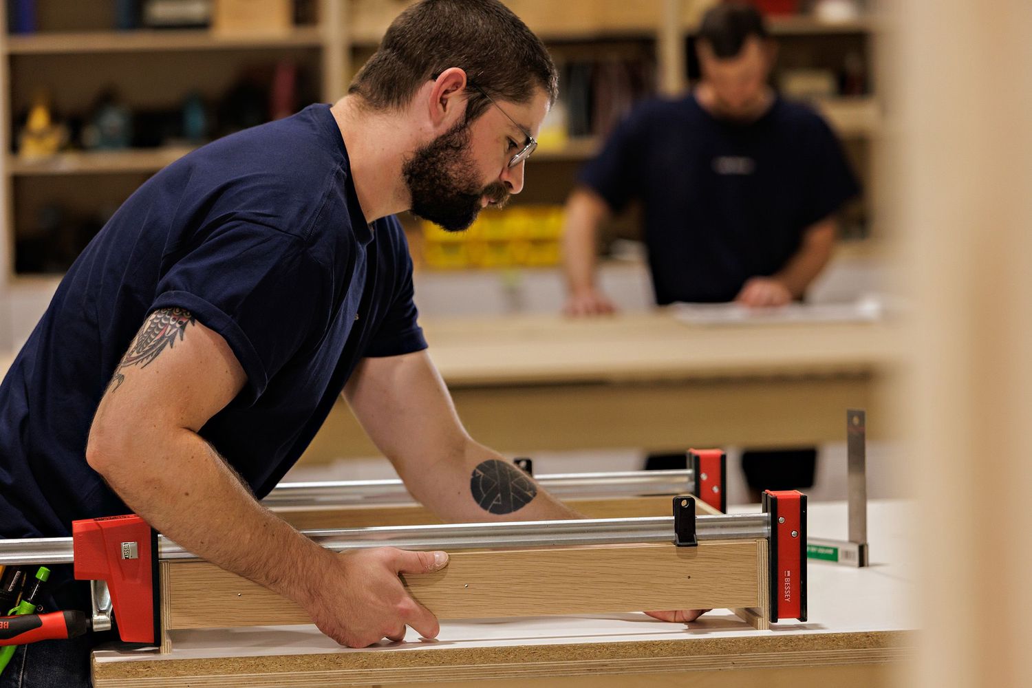 Craftsman using precision measuring tools on wooden materials in workshop setting.