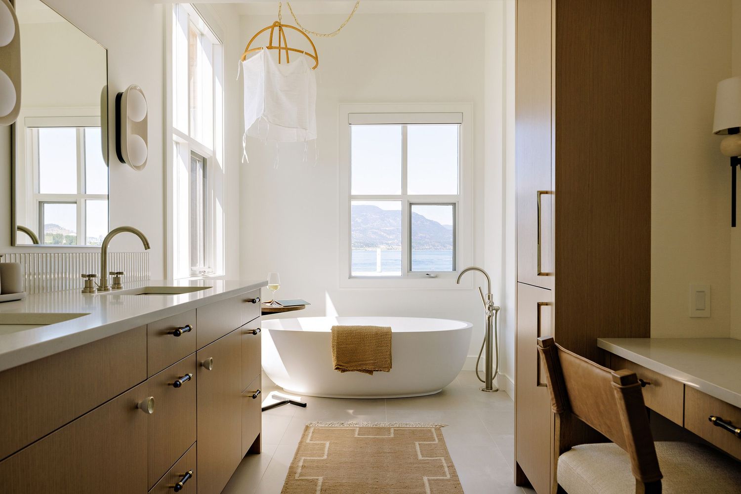 Luxurious bathroom with freestanding tub, brass fixtures, and large windows offering exterior views.