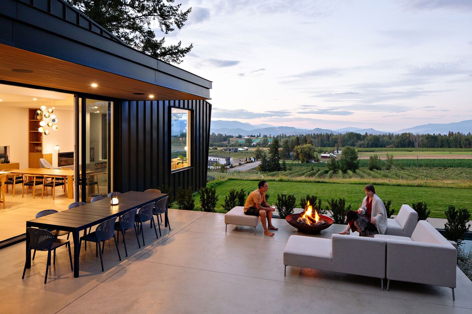 Modern outdoor living space with firepit and comfortable seating overlooking scenic mountain views at dusk.