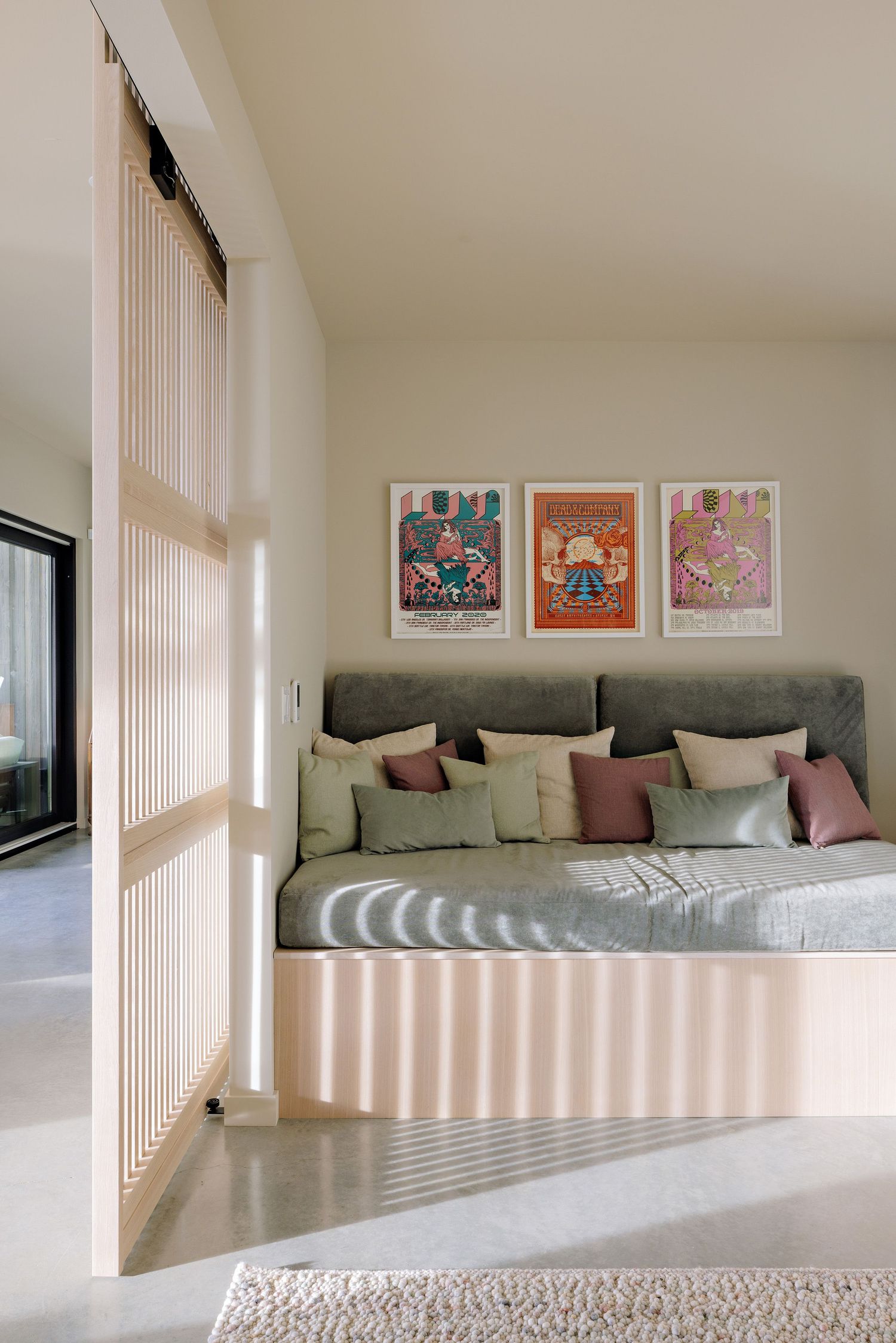 Modern reading nook with built-in bench seating, gray cushions, and three framed art prints on neutral walls.