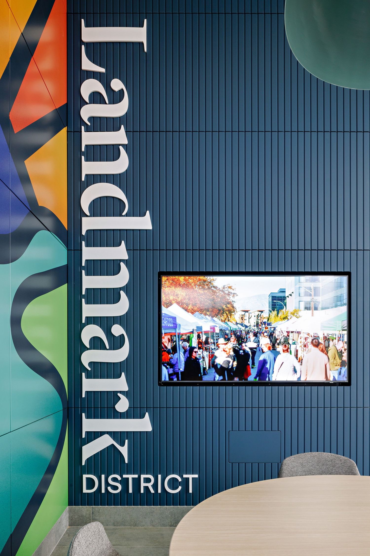 Modern office wall with 'Landmark District' signage and a mounted TV screen displaying a crowd scene.