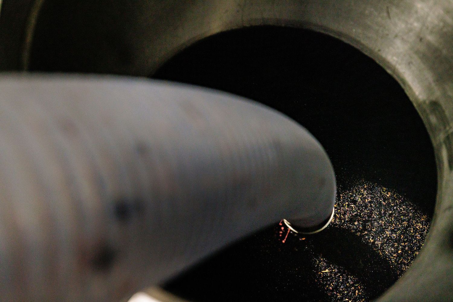 Close-up view of a vacuum cleaner hose sucking dirt and debris into a dark opening.