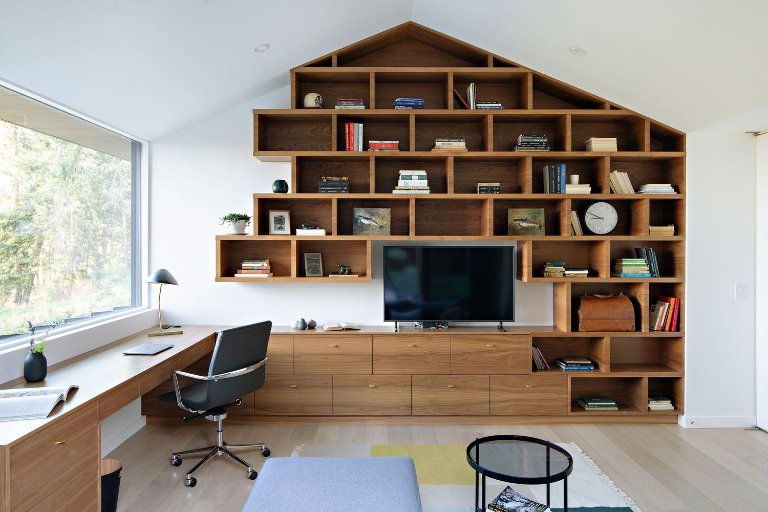 Contemporary home office featuring geometric wooden shelving and built-in desk with large window views.