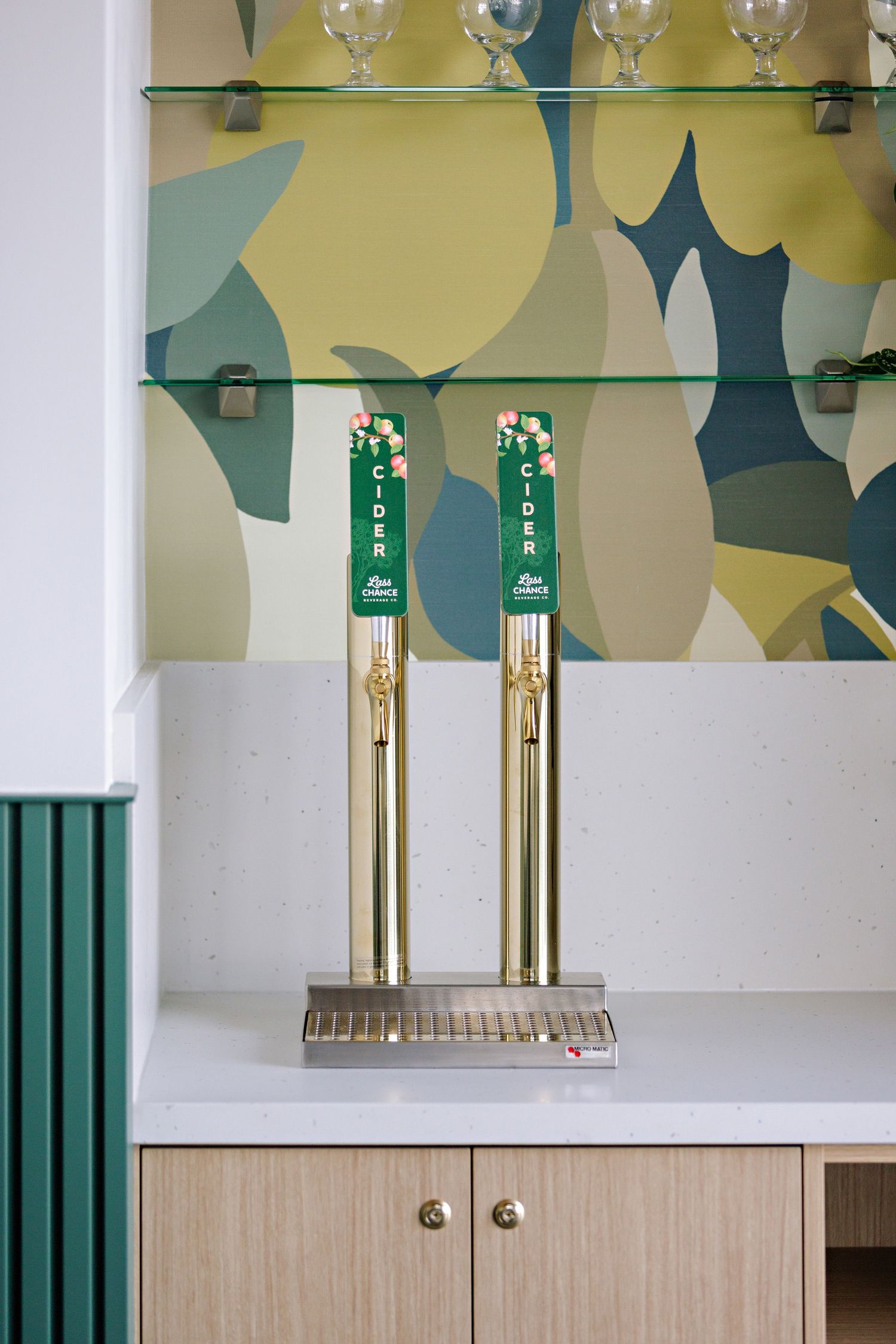 Modern bar tap setup with gold Heineken beer taps mounted on metal base against abstract wallpaper background.