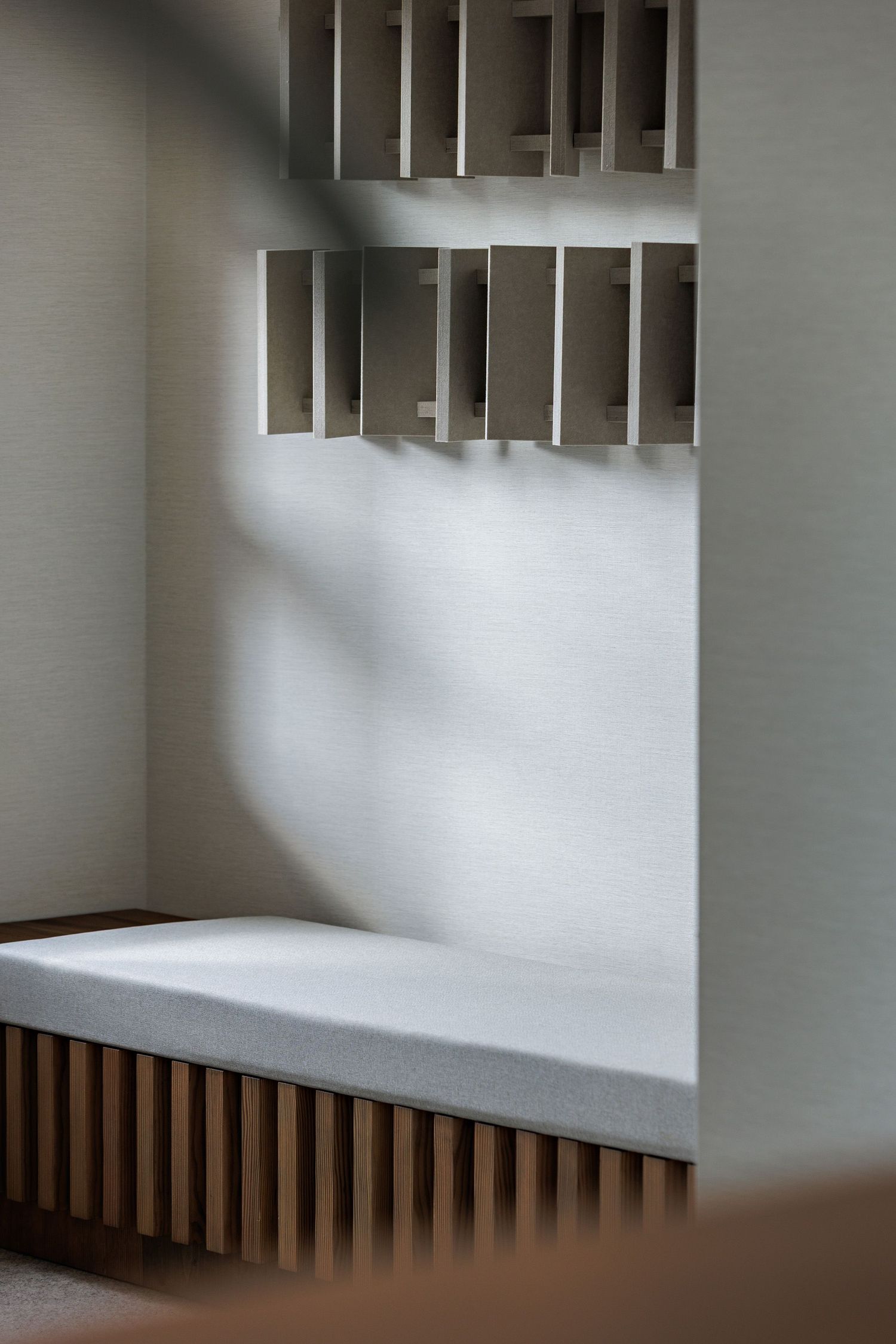 Modern architectural detail of white walls with wooden slat accents creating geometric shadows and patterns in interior space.