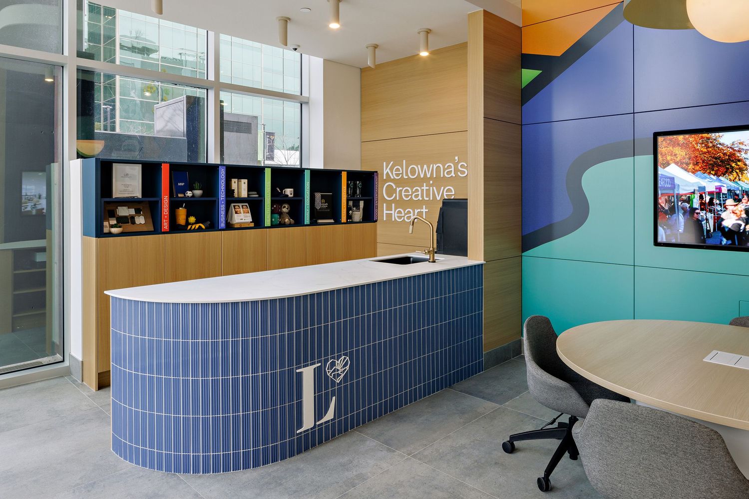 Modern office reception desk with curved blue tile front and wood accent wall featuring black storage cubbies above.