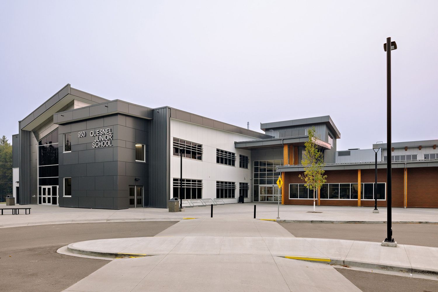Modern two-story school building exterior with contemporary architecture and clean design features a light post in front.