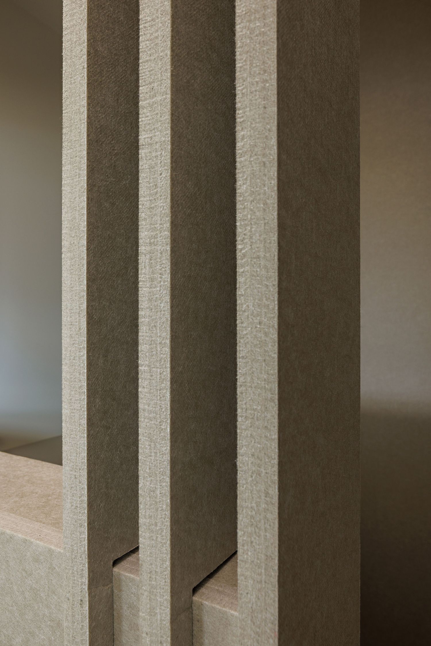 Abstract architectural detail showing vertical white columns creating a pattern of light and shadow.