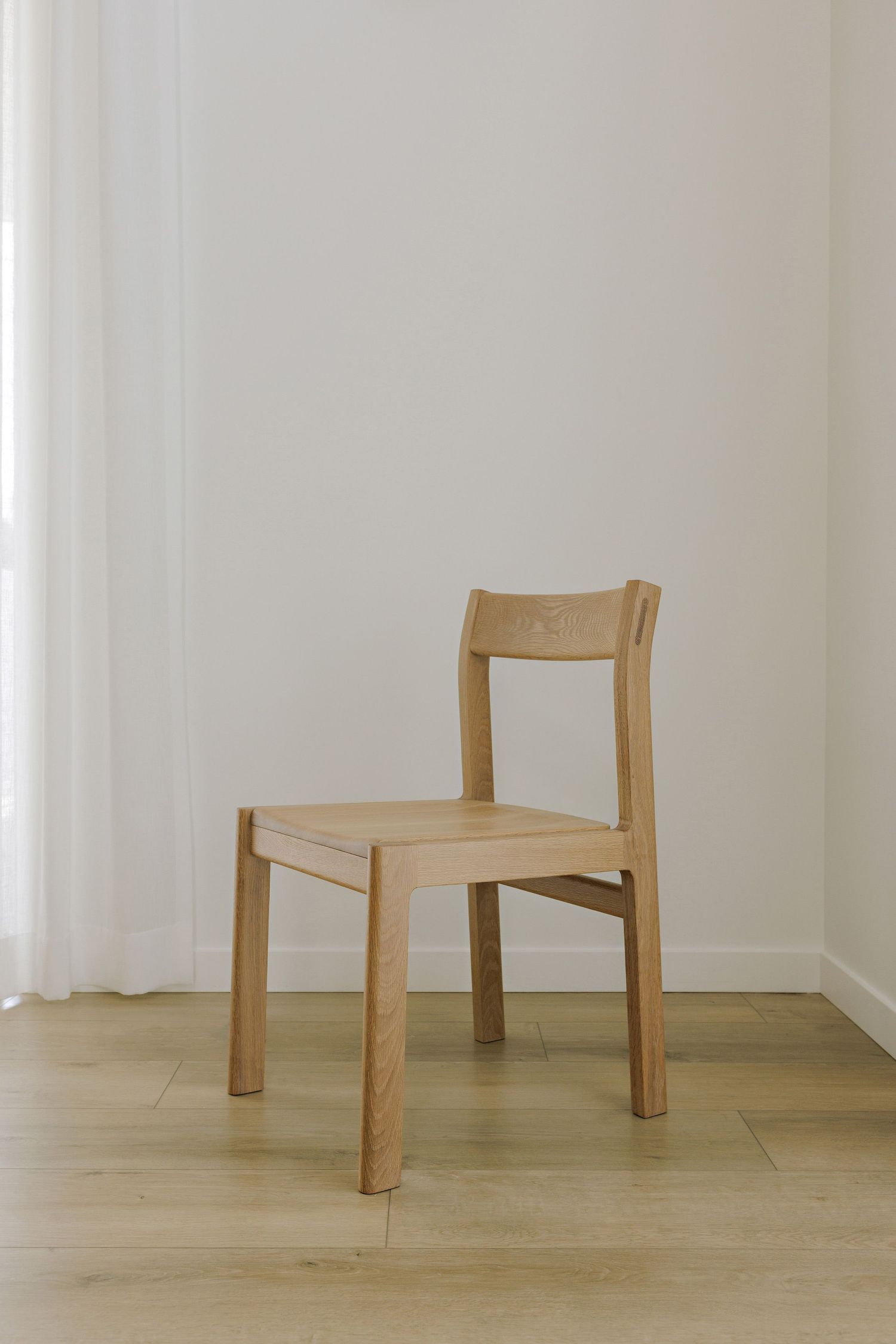 Simple wooden chairs arranged in a row against a white wall showcase minimalist furniture design.