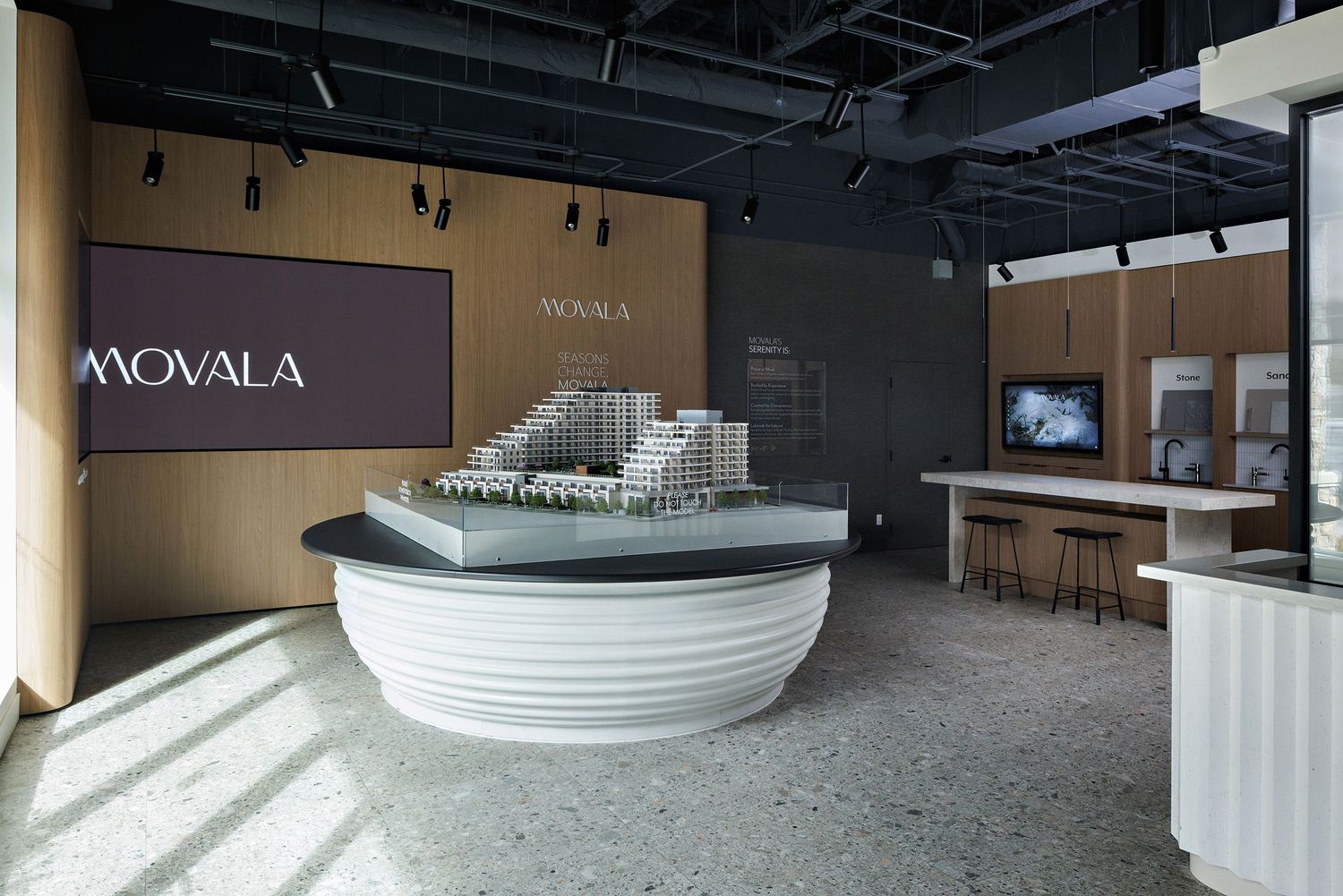 Modern office reception area with white curved desk and Movala signage on wooden wall in contemporary space.