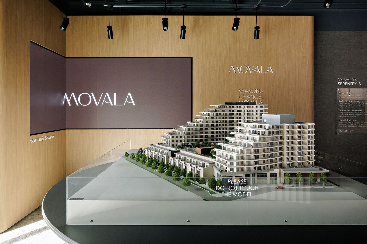Architectural scale model of a modern stepped residential building displayed in a Movala sales center presentation area.