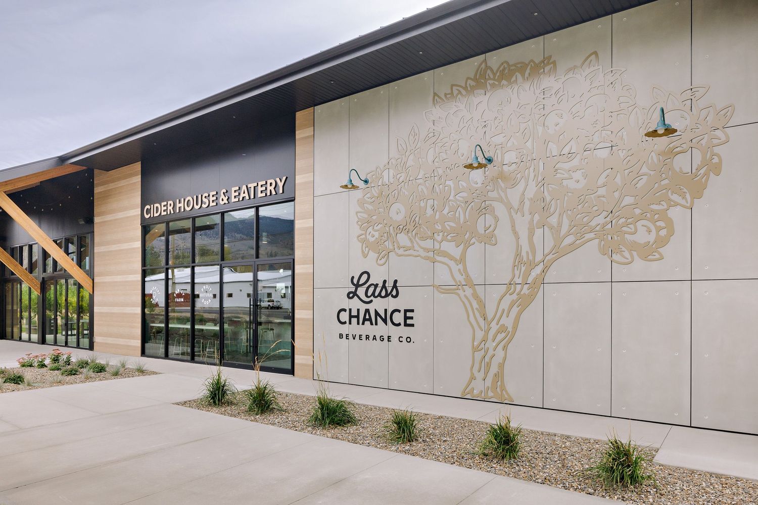 Modern commercial building exterior with 'Last Chance' text and tree artwork on a beige wall facade.